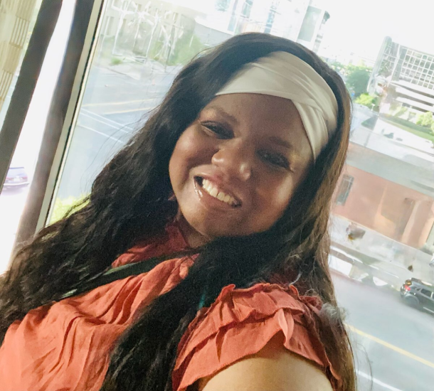 Ashley North, founder and visionary, smiling warmly in modern workspace with city views behind her.