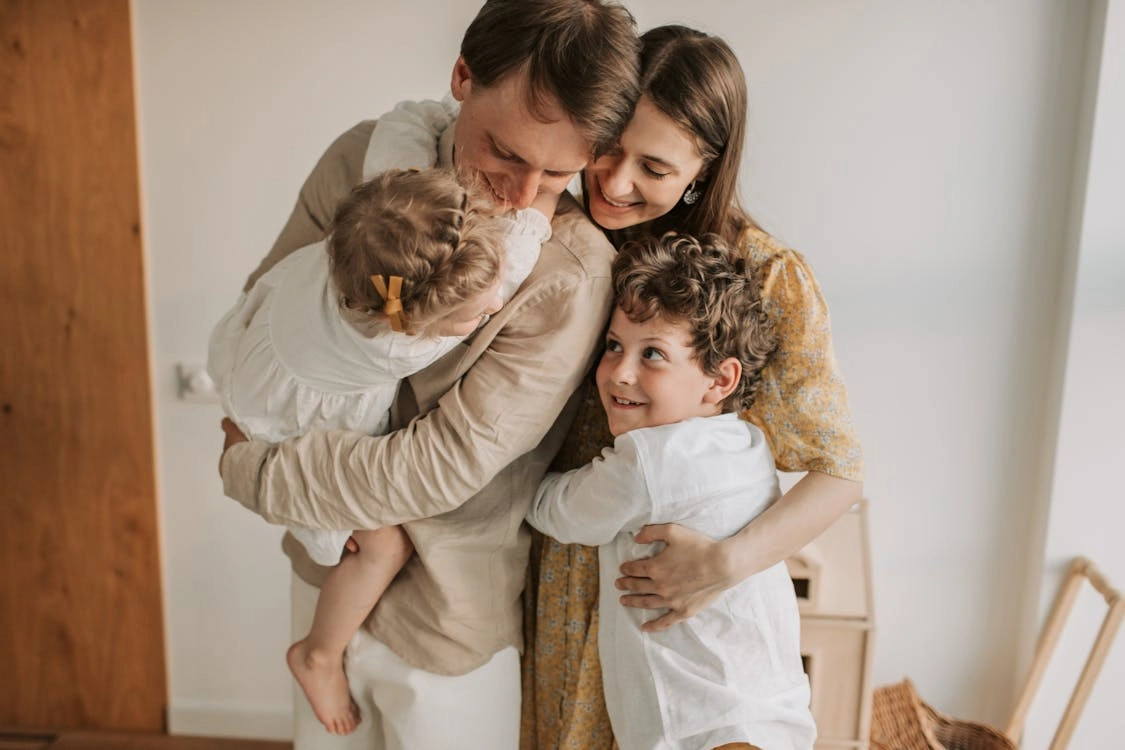 Family of four embracing joyfully in home setting, capturing love, unity, and togetherness.