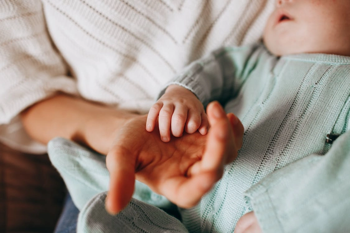 Close-up of parent holding baby’s tiny hand, symbolizing trust, care, and nurturing connection.