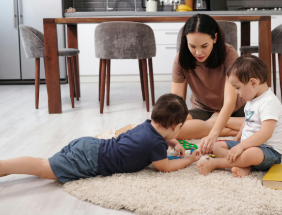 Nanny engaging children in play on living room floor, building connection and encouraging learning.