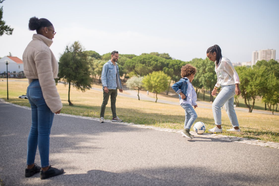 Family walking outdoors, parents and caregiver playing with children, promoting healthy family lifestyle.